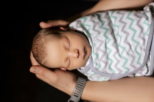 newborn baby in the arms of dad on a black background