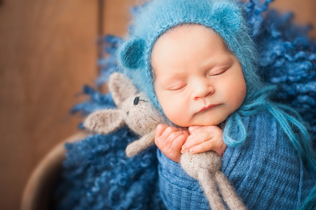 Newborn baby in blue wool in a heart-shaped basket