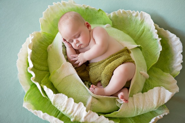 Newborn baby boy 3 months old sleeps in green cabbage. Vegetables.