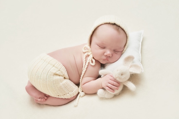 Newborn baby boy sleeping on white background. Medicine and health concept, happy motherhood and fatherhood. Kid in hat and with bunny.Easter card. Maternity hospital and clinic. Father and mother day