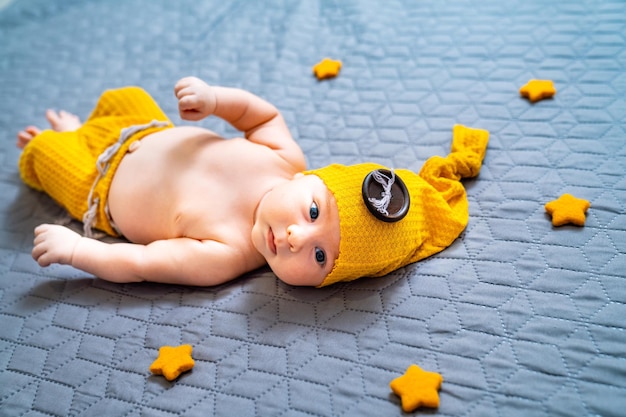 Newborn baby boy in suit on a grey background In a hat