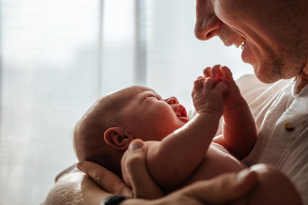 Newborn baby in dad's arms at home attention to detail closeup The concept of caring and love