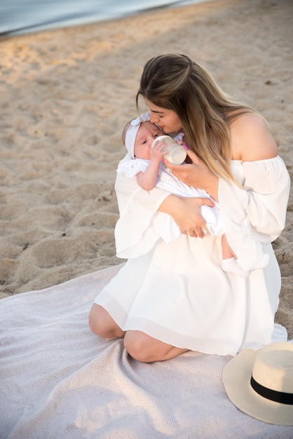 Newborn baby eats milk from a bottle flowers are nearby