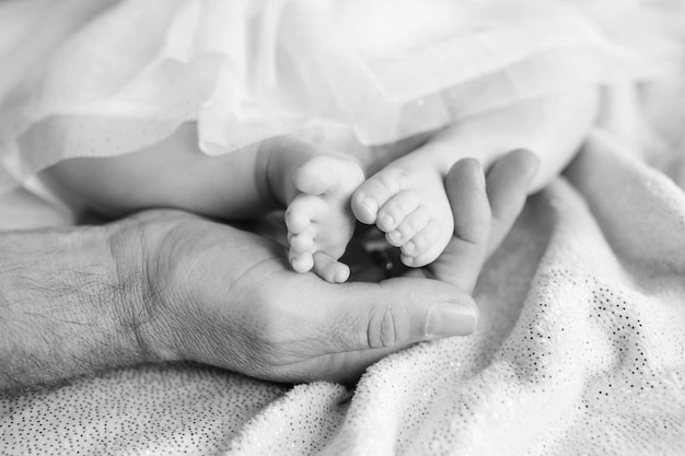 Newborn baby feet in mother hands Mother holding legs of the kid in hands Close up image