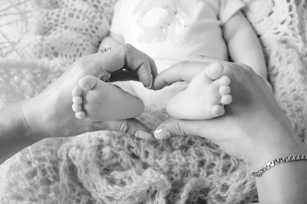 Newborn baby feet in mother hands shape like a lovely heart Mother holding legs of the kid in hands