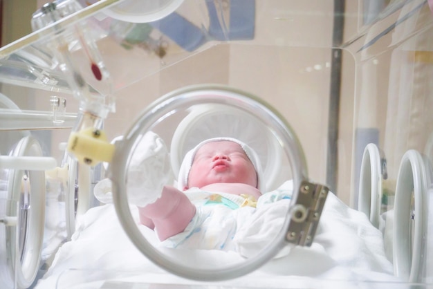 Newborn baby girl inside incubator in hospital post delivery room