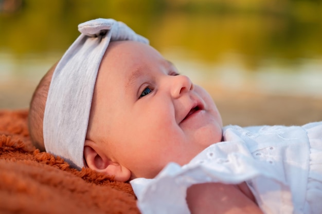 Newborn baby girl lies on the beach in a white dress