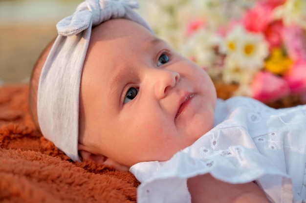 Newborn baby girl lies on the beach in a white dress