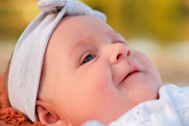 Newborn baby girl lies on the beach in a white dress