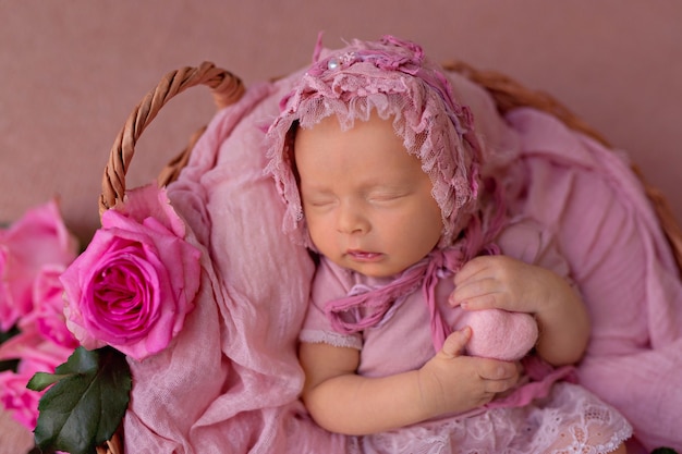 Newborn baby girl sleeping in retro basket with pink garden roses flowers