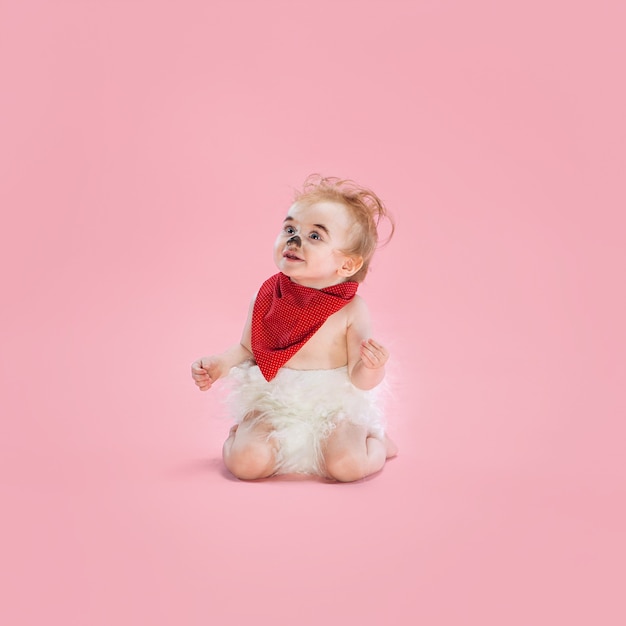 Newborn baby girl wearing a Halloween costume on pink studio background