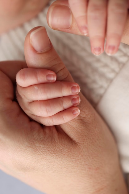 The newborn baby has a firm grip on the parent39s finger after birth Closeup little hand of child and palm of mother and father Parenting childcare and healthcare concept Professional macro photo