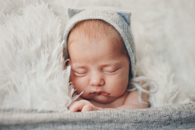 A newborn baby in a knitted hat with ears. Imitation of a baby in the womb. Portrait of a newborn.. The concept of health , parenting, children's Day, medicine, IVF