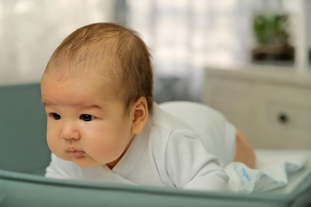 Newborn baby lies on the changing table shows emotions newborn baby learns to hold his head