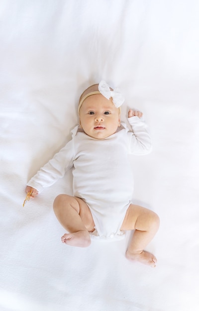 A newborn baby lies on a white bed