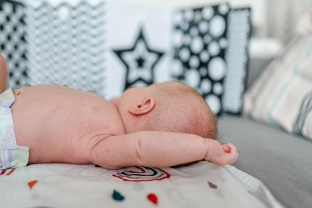 A newborn baby lies with his back to the camera and looks at the developing contrasting pictures