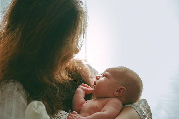 Newborn baby in mom's arms at home mother hugs baby