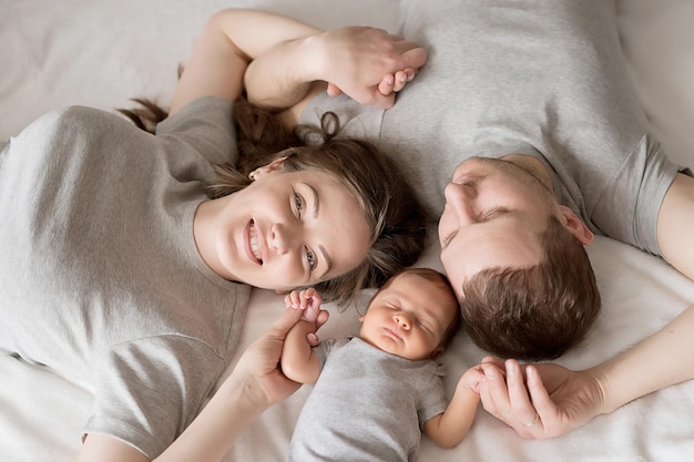 Newborn baby in mother's and father's arms on bed Postcard Mother's and father's day Children Protection Day World Happiness Day Smiling child Happy parenthood