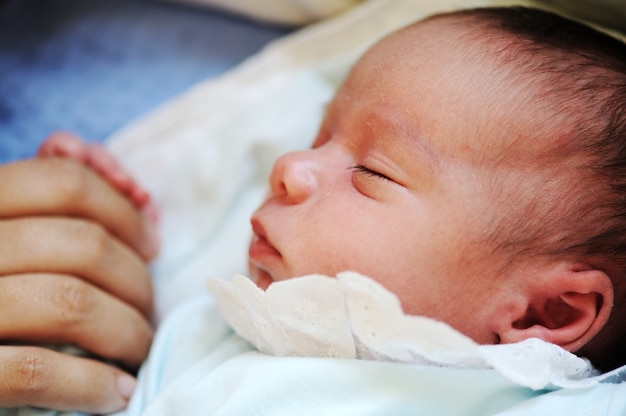 Newborn baby sleeping on bed with mom