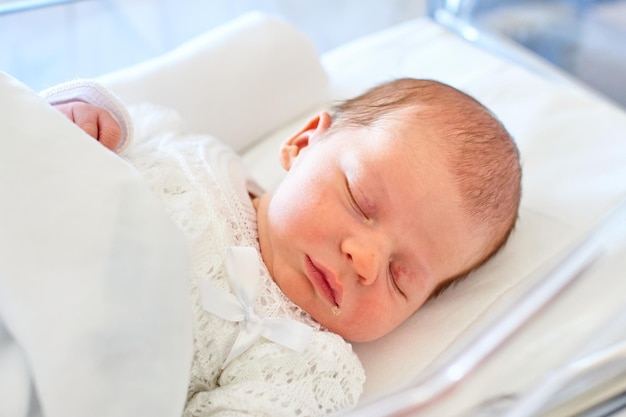 Newborn baby sleeping in its hospital crib