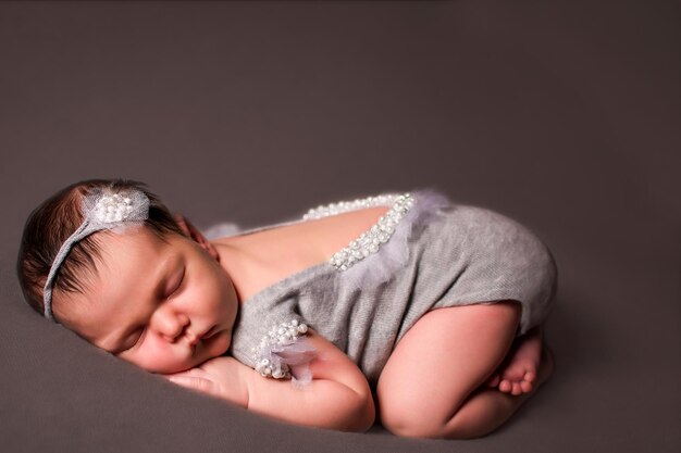 Newborn baby sleeps lies on a gray background