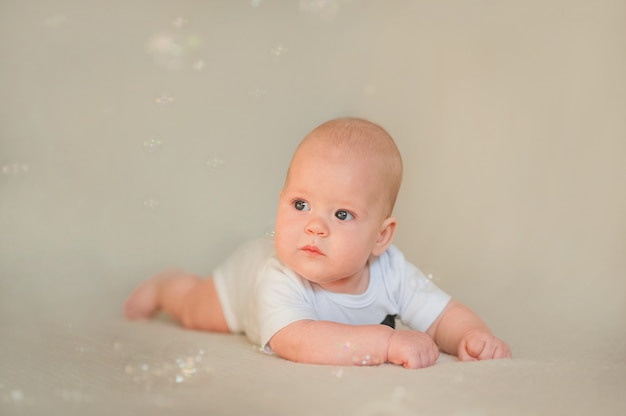 Newborn baby in white bodysuit and tie.