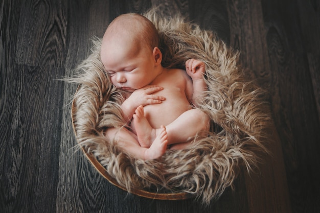 Newborn baby wrapped in a blanket sleeping in a basket.