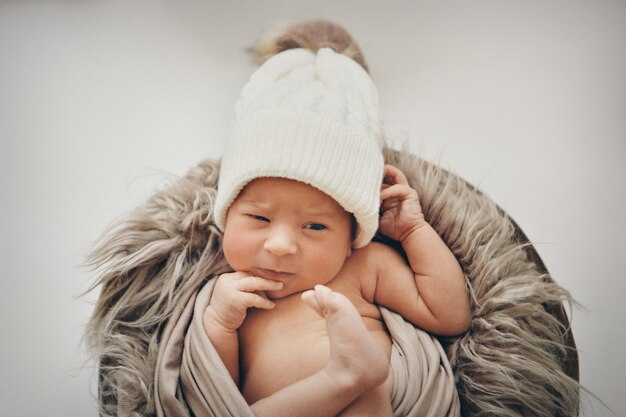 A newborn baby wrapped in a blanket with a warm hat on his head. the  childhood, health, IVF.