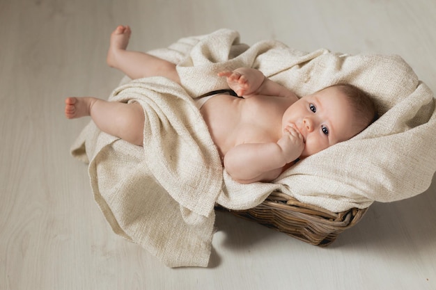 Newborn baby wrapped in a linen blanket lies in a wicker basket cradle. products for children. concept of healthy sleep and child development. happy childhood and motherhood. High quality photo