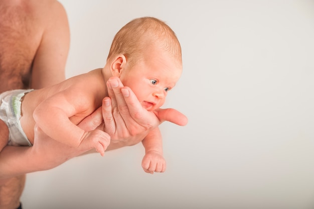 Newborn on the bed with his father close-up. The concept of the relationship of children and parents from birth.