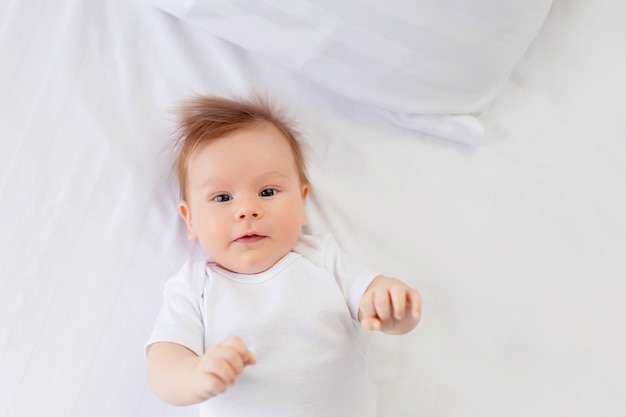 A newborn boy is resting in bed, lying on his back in bed. Infant.