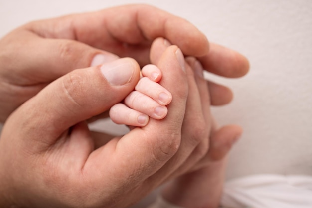 A newborn holds on to mom39s dad39s finger Hands of parents and baby close up A child trusts and holds her tight Tiny fingers of a newborn The family is holding hands Concepts of family and love