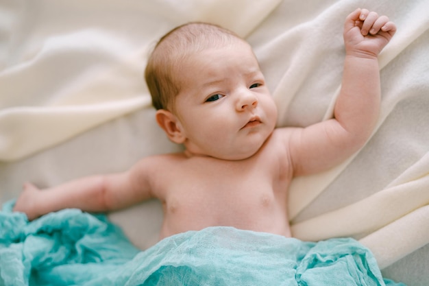 Newborn lies on a beige blanket closeup