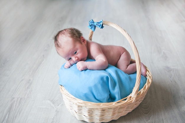 Newborn small baby boy in basket blue eyes and colors kid happily smiling and looking at camera