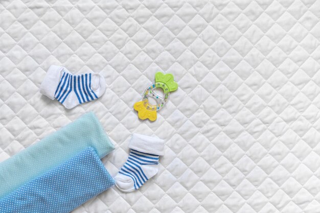 For a newborn socks blue diapers a teether lace on a white textured background Copy space