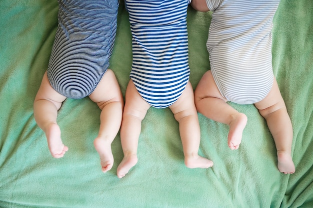 Newborn triplets lie on a stomach on a blanket