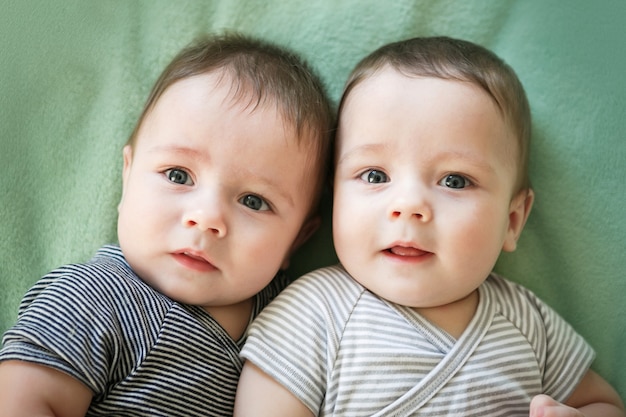 Newborn twins boys are lying on the bed