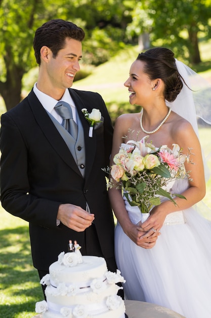 Newlywed couple with wedding cake at park