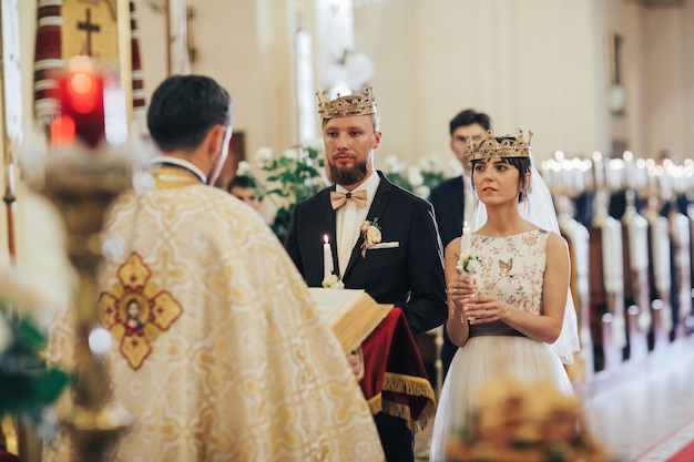 Newlyweds in the church. Priest celebrate wedding mass at the church