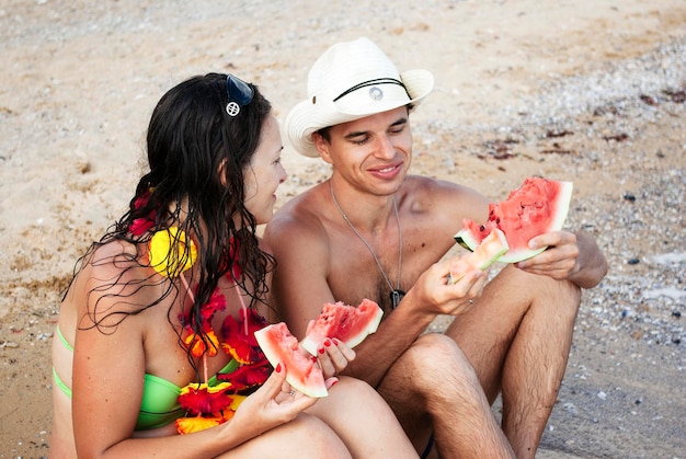 Newlyweds eat watermelon on the beach