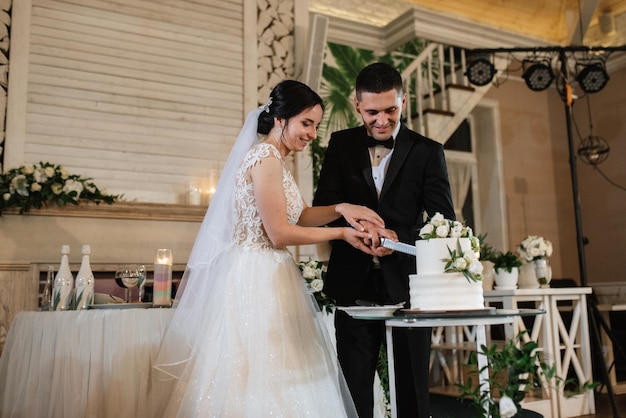 Newlyweds happily cut laugh and taste the wedding cake