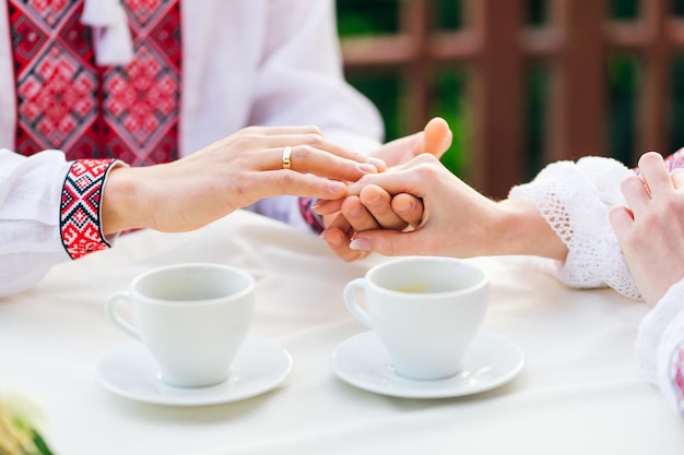 newlyweds holding hands and wedding ring on ring finger guy and girl in cafe drinking hot coffee