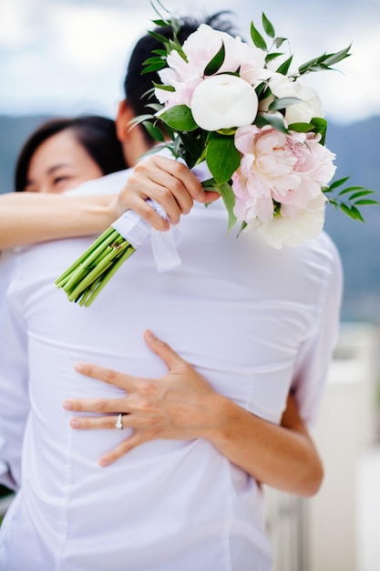 Newlyweds holding wedding bouquet together