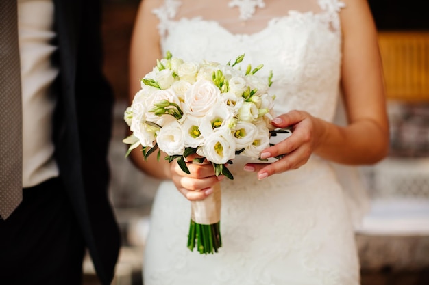 Newlyweds holding wedding bouquet together