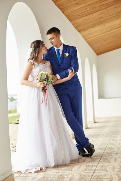 Newlyweds hug and kiss near lighthouse at wedding