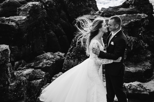 Newlyweds hug and smile on the background of large stones profi