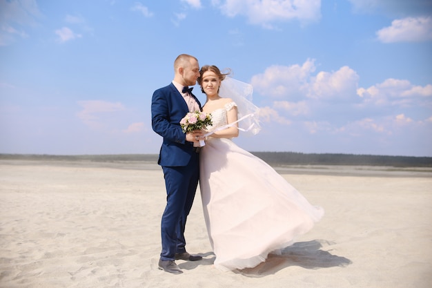 Newlyweds posing together on the beach