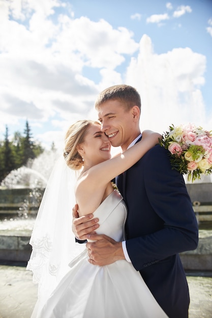 Newlyweds walk in nature in the Park after the wedding ceremony. A kiss and a hug from a man and a woman. The groom is holding his bride