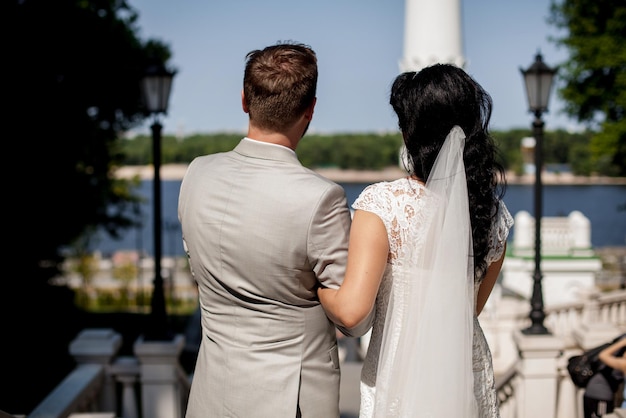 Newlyweds on the waterfront. back view. The bride and groom, embracing, look at the embankment.