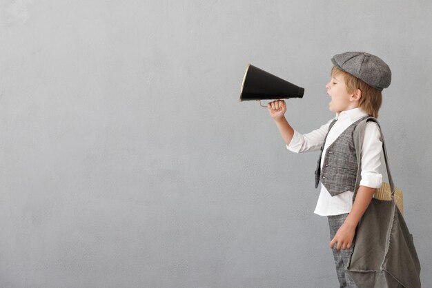 Newsboy shouting against grunge wall background Boy selling newspaper